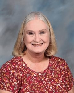 Smiling mature woman in red floral top against blurry background