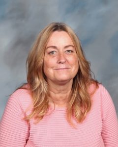 Woman in pink sweater smiling against blurry background
