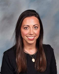 Smiling professional woman with long brown hair wearing black top