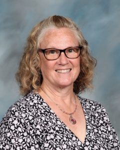 Smiling woman with glasses wearing black and white patterned shirt