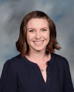 Smiling professional woman in navy top against blurred background