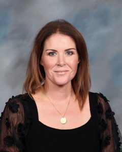 Woman in black lace top smiling against blurry background