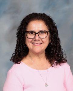 Smiling woman with curly hair and glasses wearing pink shirt