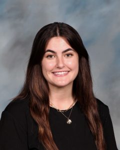 Smiling young person with long brown hair wearing black top