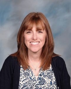 Smiling woman in navy cardigan and floral top against blurred background
