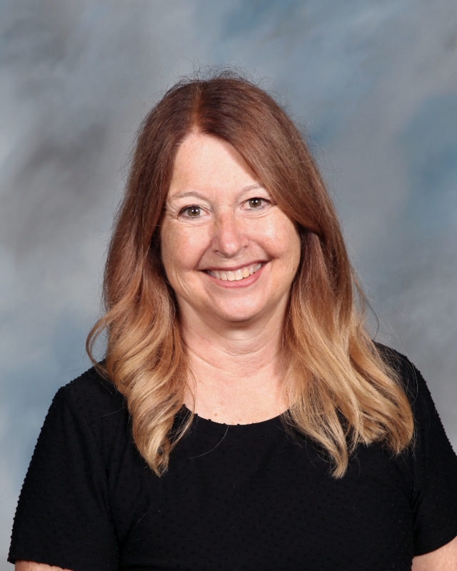 Smiling woman with ombre hair in black shirt against blurry background