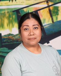 Woman in light blue shirt posing in front of colorful background